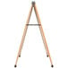 An Aarco oak A-frame sign board with a white marker board on a wooden easel with metal stand.