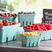 A carton of several green pulp baskets filled with fruit.