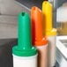A group of Carlisle Store 'N Pour containers with different colored spouts and necks.