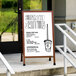 A cherry A-Frame sign with a white marker board on the sidewalk with a drawing of a pot.