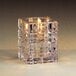 A Sterno clear glass Krystle square liquid candle holder with a lit candle inside.