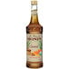 A 750 mL bottle of Monin Organic Caramel Flavoring Syrup with brown liquid.