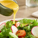 A bowl of salad with Monin Passion Fruit Puree being poured over it.