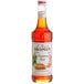 A bottle of Monin Cinnamon Bun flavoring syrup with a white label.