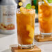 A glass of iced tea with Monin Peach Fruit Puree on top of the fruit.