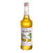 A close up of a Monin Mango Fruit Syrup bottle filled with yellow liquid.