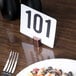 A round hammered copper table card holder with a number on it in a plate of food.