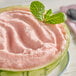 A watermelon with pink ice cream and mint leaves inside.
