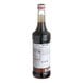 A Monin bottle of dark chocolate syrup with a white label.
