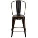 A distressed copper metal restaurant bar stool with a back.