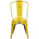 A yellow metal chair with a vertical slat back and drain hole seat.