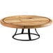 A round wooden Cal-Mil Madera cake pedestal on a table with black legs.