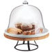 A Cal-Mil Madera rustic pine cake pedestal with a glass dome over pastries on a table.