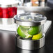 A Cal-Mil Luxe jar with a notched lid containing lime slices and a lime.