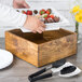 A wooden box with strawberries on a Cal-Mil rustic pine cooling base.