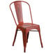 A red metal Flash Furniture restaurant chair with a slat back and drain hole seat.