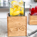 A glass jar filled with lemon slices in a wooden container.