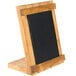 A wooden Cal-Mil Madera stand with a black chalkboard on a table.