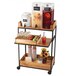 A Cal-Mil clear acrylic beverage dispenser with ice in it on a wooden cart with drinks and fruit.