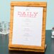 A wooden table with a Cal-Mil Madera wood displayette holding a menu