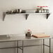 A Regency stainless steel wall shelf holding food items.