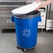 A person putting a white lid on a blue recycling bin.