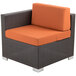 A BFM Seating Aruba wicker armchair with orange cushions.