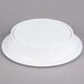 A white Elite Global Solutions round melamine pedestal plate on a gray surface.