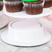 A hand holding a white plate with cupcakes on a white Elite Global Solutions M5P pedestal.