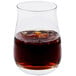 A Spiegelau whiskey tumbler with brown liquid and ice.