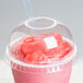 A Dart clear plastic cup lid with a straw hole on a plastic cup with a pink drink.