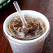A Solo clear plastic lid with a straw slot on a plastic cup with a straw and ice.