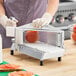 A commercial-grade tomato slicer with a metal frame and multiple blades for evenly slicing tomatoes.