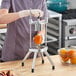 A metal 8-section fruit and vegetable wedge cutter being used to slice an orange.