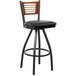 A BFM Seating black metal bar stool with a cherry wood back and black vinyl seat.