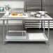 A Steelton stainless steel work table with an undershelf in a professional kitchen with bowls on it.