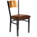 A BFM Seating black metal side chair with a natural wood back and light brown vinyl seat.