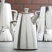 A group of Vollrath stainless steel coffee pots on a table.