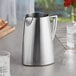 A close-up of a stainless steel Vollrath Triennium water pitcher.