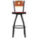 A BFM Seating black metal bar stool with a cherry wooden back and swivel seat.