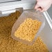 A hand holding a Rubbermaid white plastic container of pasta.