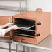 A woman holding a tray of food in a Cambro insulated tray carrier.