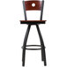 A BFM Seating black metal bar stool with a mahogany wood swivel seat and back with a hole in it.