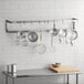 A kitchen with Regency stainless steel pot racks holding pots and pans on a wall.