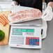 A person weighing a large piece of meat on a Cardinal Detecto legal for trade scale.