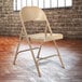 A beige National Public Seating metal folding chair.