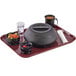 A Cambro dark cranberry rectangular non-skid tray with bowls of fruit and vegetables on it.