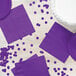 Amethyst purple napkins and confetti on a table.