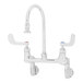 A silver T&S wall mounted surgical sink faucet with 4" wrist action handles.