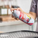 A person spraying Grid Iron Sprease panini grill and waffle iron release spray onto a grill pan.
